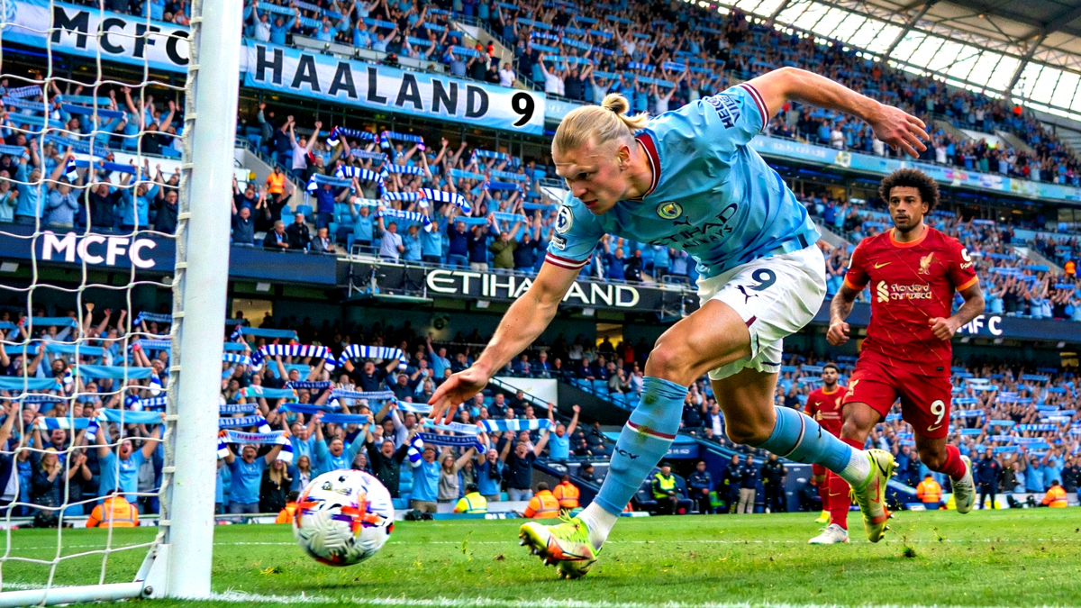 英超第9轮曼城主场对阵利物浦的激烈比赛瞬间，哈兰德在禁区内射门得分，背景是伊蒂哈德球场沸腾的蓝色海洋球迷